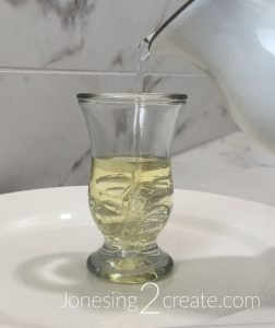 Pouring water into the glass with oil in it